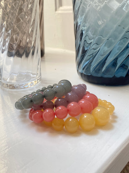lemonade mega bracelets in colours honey , rhubarb, plum and eucalyptus. Displayed next to swirly glasvases, stilleben design