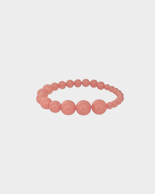 A  beaded stretch bracelet in rhubarb colour with alternating large and small polished round resin beads, made by lemonade ltd. Made in copenhagen denmark