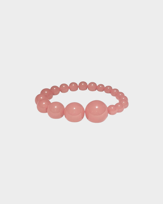 A  beaded stretch bracelet in rhubarb colour with alternating large and small polished round resin beads, made by lemonade ltd. Made in copenhagen denmark